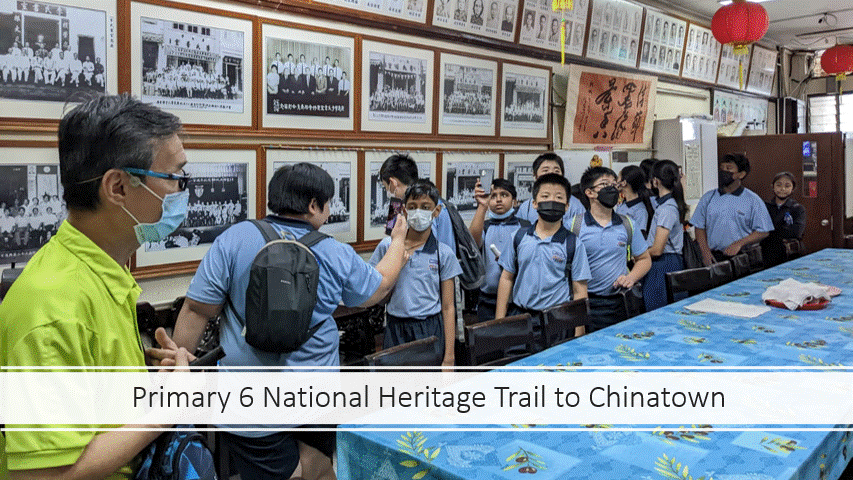 A guide in yellow speaks to uniformed Primary 6 students wearing masks inside a room lined with framed photos.
